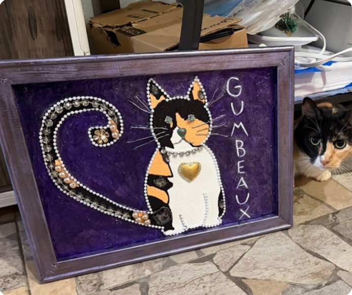 A jeweled painting of Queen Gumbeaux, with her peeking out beside it